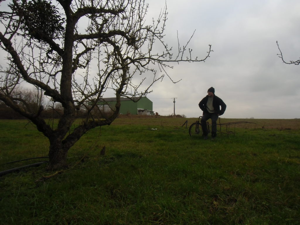 Xavier devant une de ses parcelles en vergers, avec son bâtiment de ferme en arrière-plan. Crédits photo : Nicolas Patissier pour Studio Zef